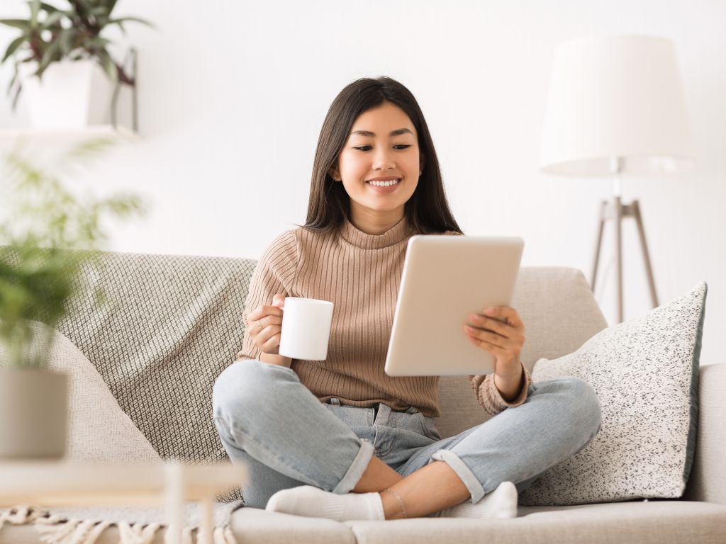 Leitora sorrindo enquanto lê em um tablet, engajada com a história.